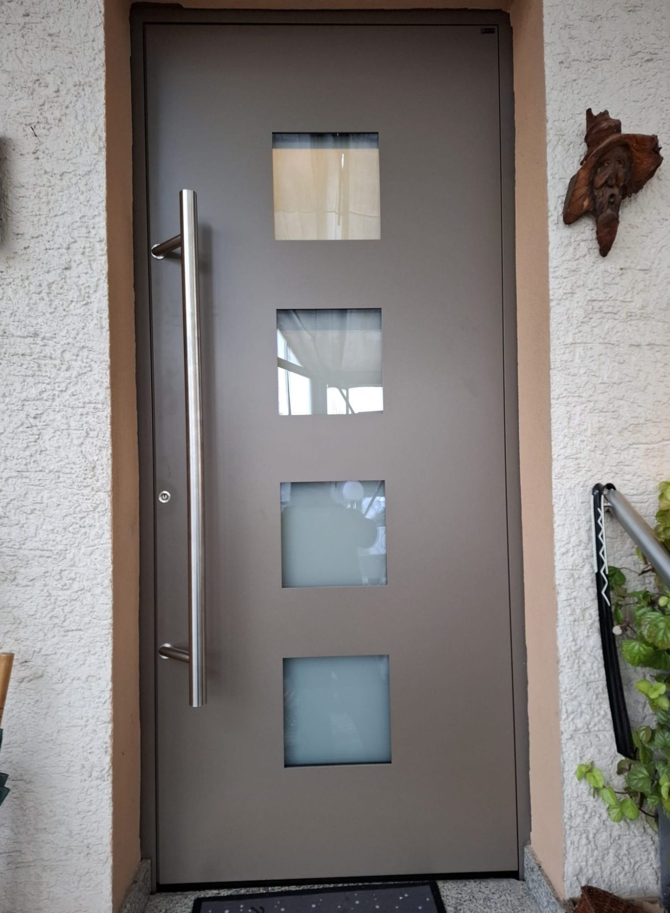 Haustür mit Glaseinsätzen Graue Haustür mit drei quadratischen Glaseinsätzen und langem Edelstahlgriff
