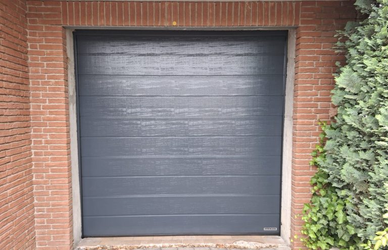 Anthrazitfarbenes Sektionaltor in einer Garage mit roter Ziegelfassade