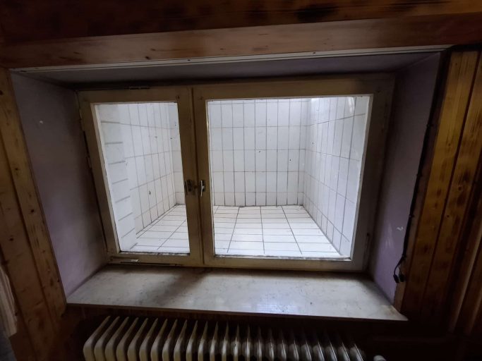 Vorher Vorher: älteres zweiflügeliges Fenster mit braunem Rahmen in einem holzverkleideten Raum