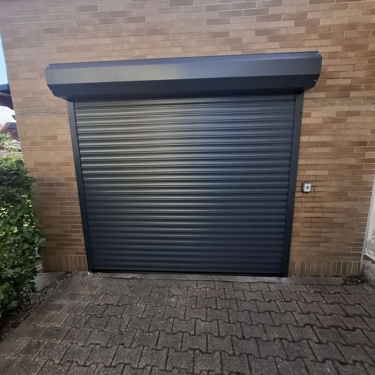 Anthrazitfarbenes Rolltor vor einer Garage mit Ziegelfassade
