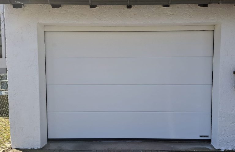 Weißes Sektionaltor an einer Garage mit heller Fassade