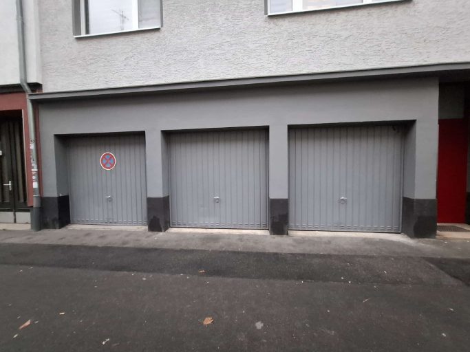 Vorher Vorher: drei graue Schwingtore mit senkrechten Sicken und Griffen an derselben Garagenfront